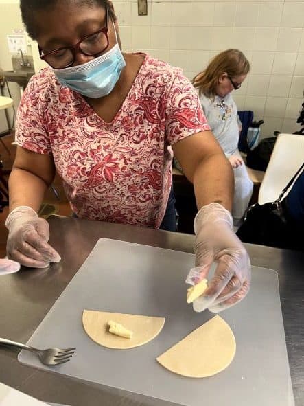 Woman adding ingredients to dough.