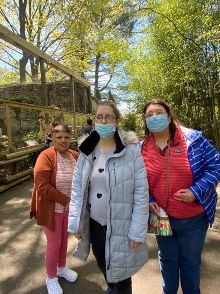 Three women wearing masks standing in the zoo.