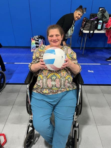 Woman sitting in a wheelchair holding a basketball.