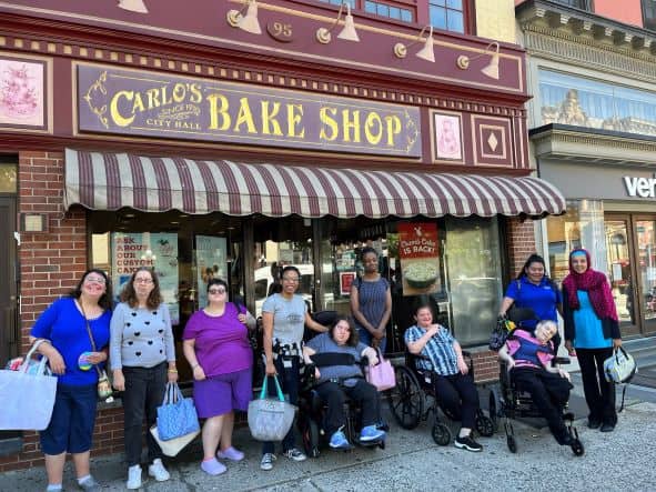 Large group of women in front of Carlo's Bake Shop.