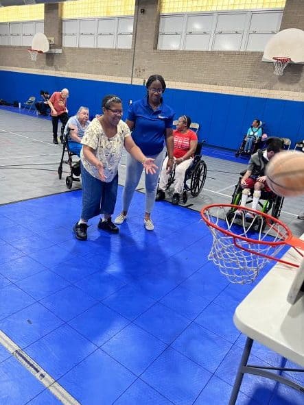 A developmentally disabled woman smiling after shooting a basketball into the basket.