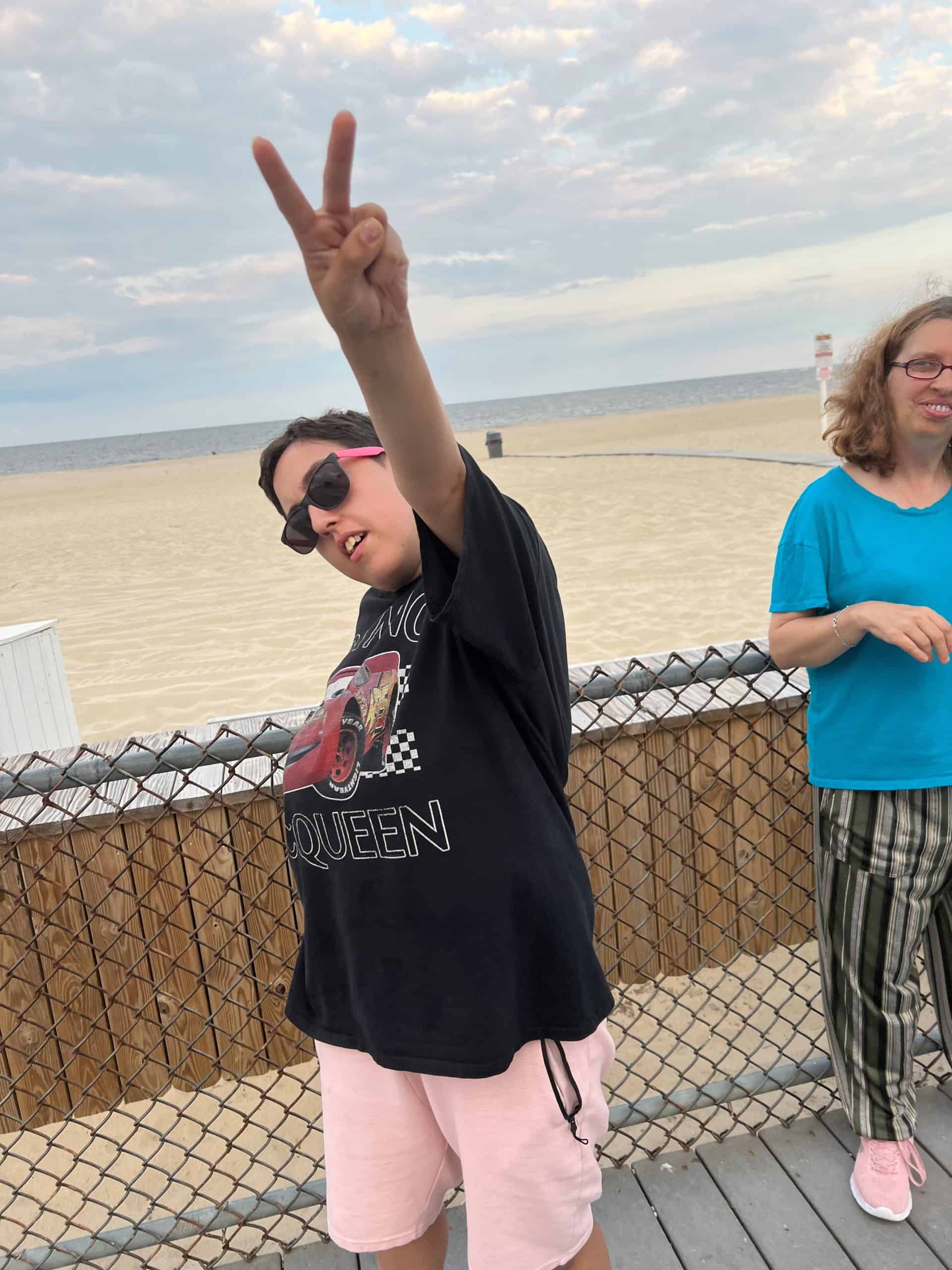 Young woman holding up a peace sign on the boardwalk.